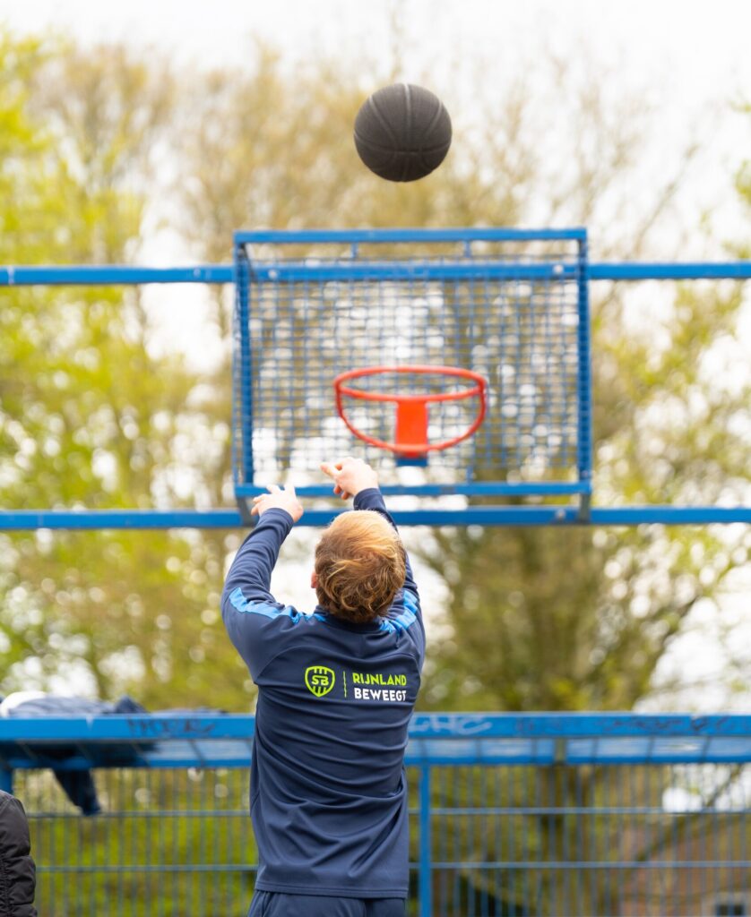 Buurtsportcoach doet schot op basket